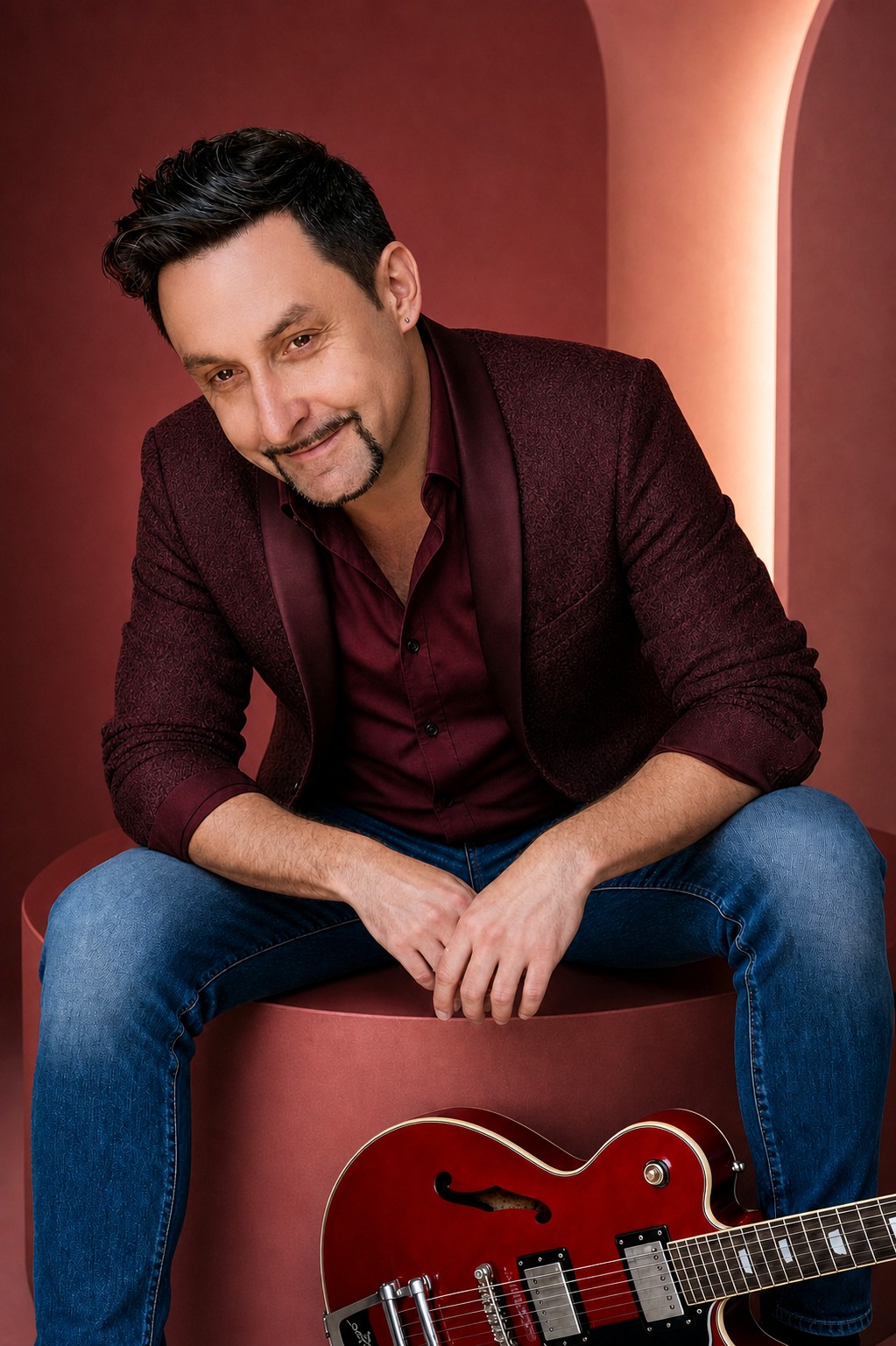 Denny Schönemann im weinroten Outfit vor modernem Studiohintergrund