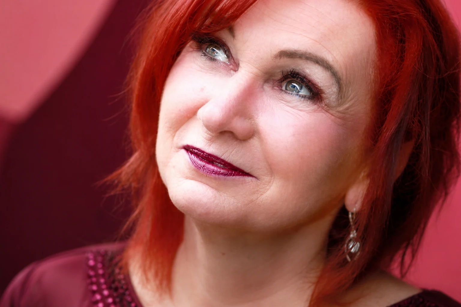 Nahporträt von Sandy van Ry vor roséfarbenem und weinrotem Studiohintergrund